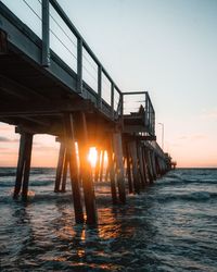 Pier over sea against sky during sunset