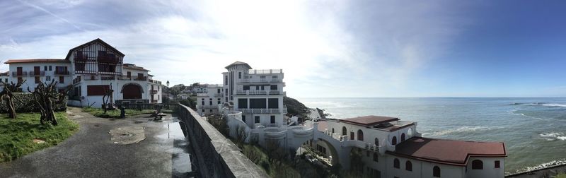 Buildings by sea against sky