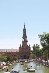 View of building by canal against clear sky