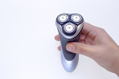 Close-up of hand holding camera over white background