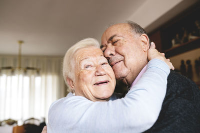 Affectionate senior couple hugging at home