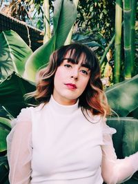 Portrait of young woman standing against plants