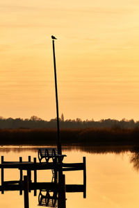 Silhouette pier on lake against sky during sunset