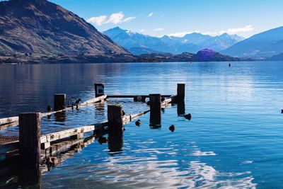 Wooden posts in lake against sky