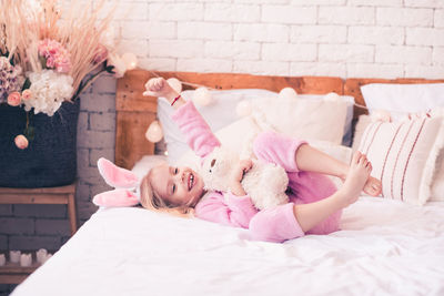 Carefree girl playing with teddy bear at home