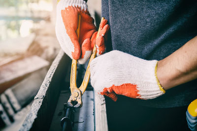 Midsection of man working on metal with pliers