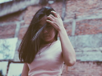 Low angle view of beautiful young woman standing against wall