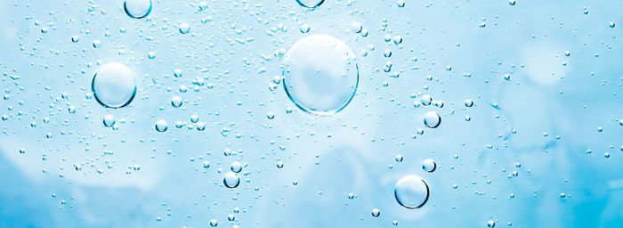 Full frame shot of wet glass against blue background