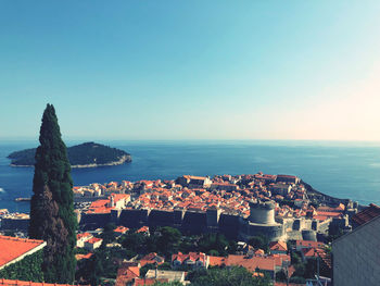 Aerial view of townscape by sea against clear sky