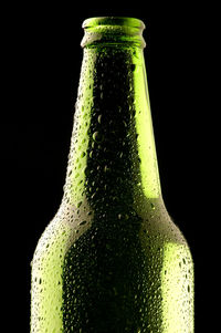 Close-up of green glass bottle against black background