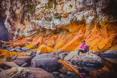 Rear view of woman sitting on rock