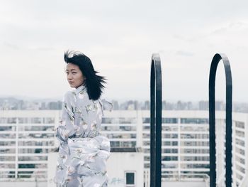 Young woman standing against sky