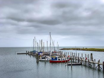 Fishing boats in sea against cloudy sky