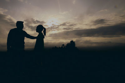 Silhouette couple standing against sky during sunset