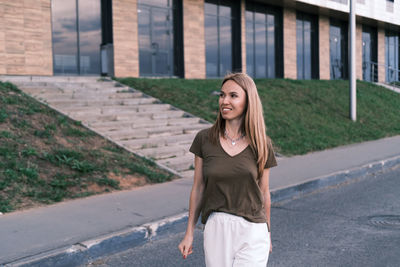 Portrait of smiling young woman standing against building