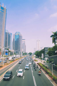 Traffic on road amidst buildings in city against sky