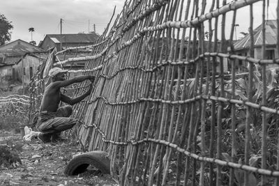 Low angle view of a farmer fixing his fence of bamboo tree