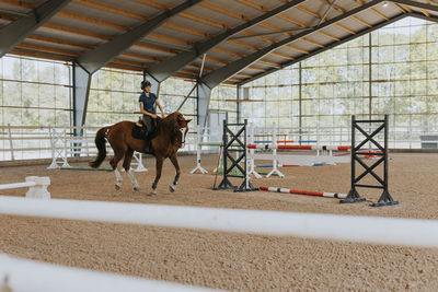 View of female horse rider using indoor riding paddock