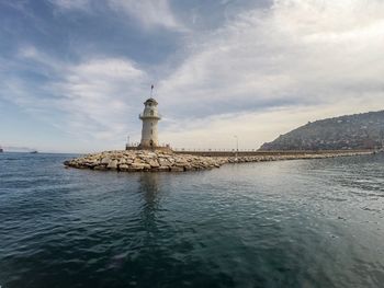 Lighthouse by sea against sky