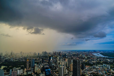 Aerial view of cityscape against cloudy sky