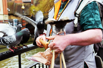 Man feeding pigeons by railing