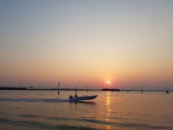 Silhouette boats in sea against clear sky during sunset