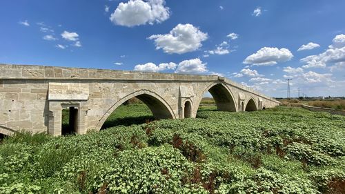 Arch bridge on field against sky