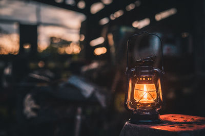 Close-up of illuminated lantern on table during sunset