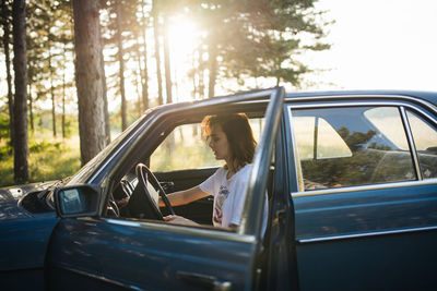 Woman sitting in a parked broken car.