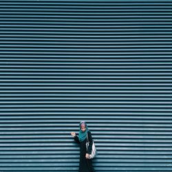 Full length portrait of woman against blue wall