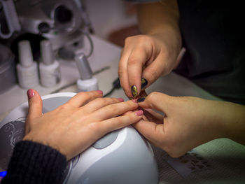 Close-up of stylist doing nail art of woman at table
