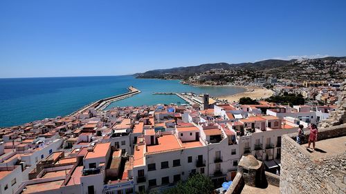 Aerial view of townscape by sea against clear blue sky