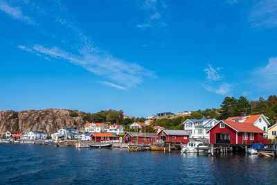 Houses by buildings against blue sky