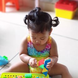 Cute girl playing with toy sitting on floor