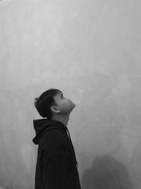 Side view of young man looking away against wall