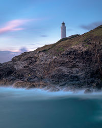 Lighthouse by sea against sky