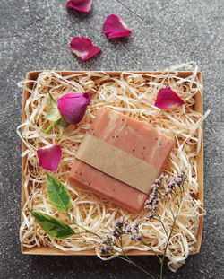 Natural handmade soap with rose petals on straw background