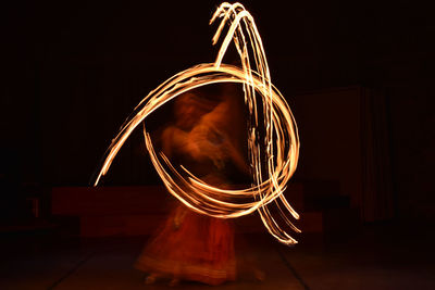 Long exposure shot of fire dancer dancing and forming symbol