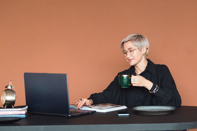 Fashion woman in black shirt working in modern work place or office with laptop and coffe cup