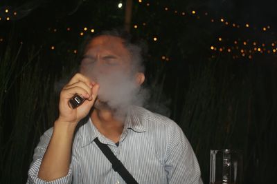 Portrait of man smoking while holding camera