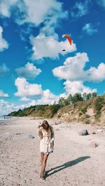 Woman standing on beach against sky