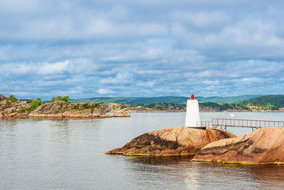 Lighthouse by sea against sky