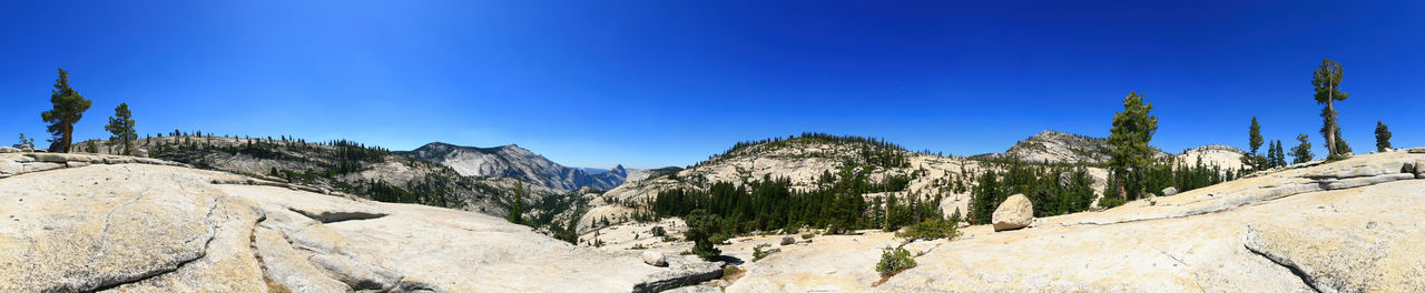 Panoramic view of trees and mountains against blue sky