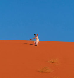 Full length of man on sand dune against clear sky