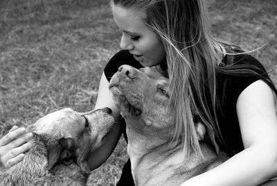Close-up of young woman embracing dogs on field