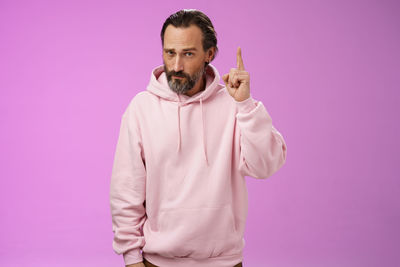Portrait of man standing against pink background