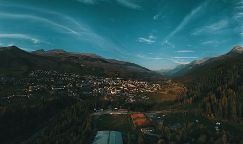 Aerial view of townscape by mountains against sky