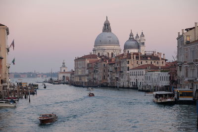 Boats in canal by buildings in city