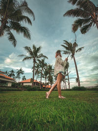Woman standing by palm trees against sky