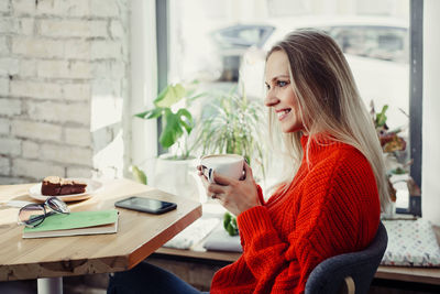 Pretty young women drinking hot coffee in cafe. person holding cup of cappuccino over the window